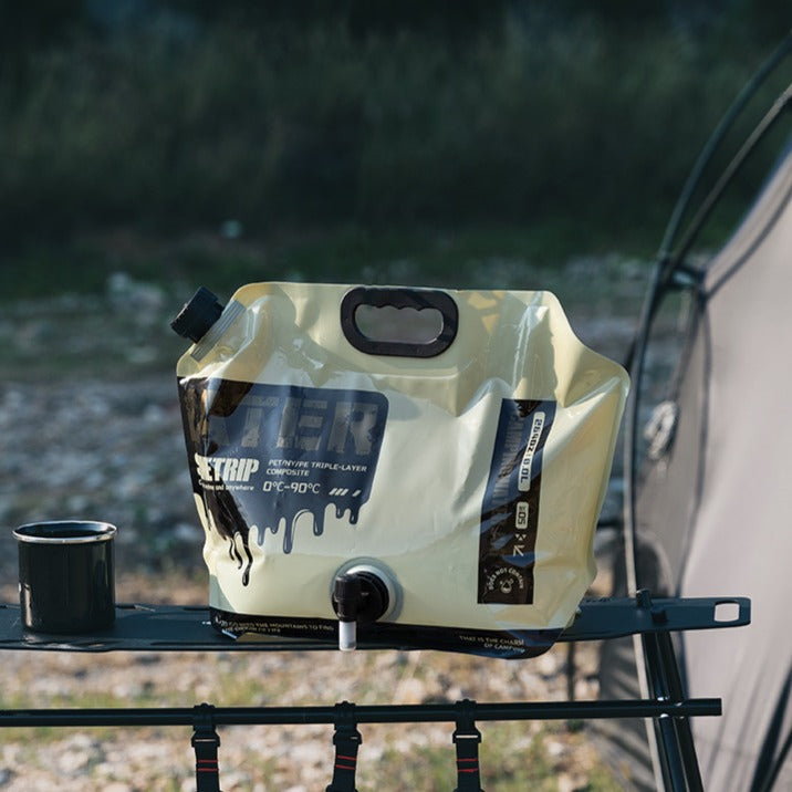 8L foldable water container beige version placed on camping table portable outdoor water storage bag