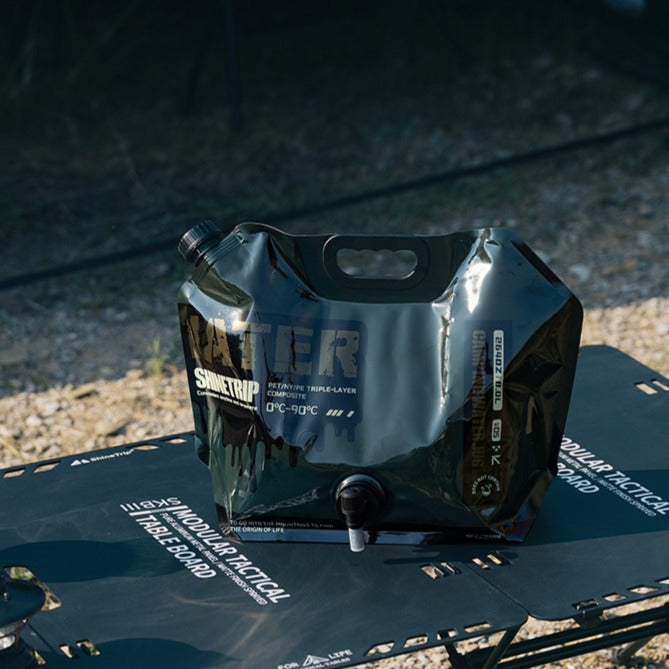 8L foldable water container black version placed on camping table portable outdoor water storage bag