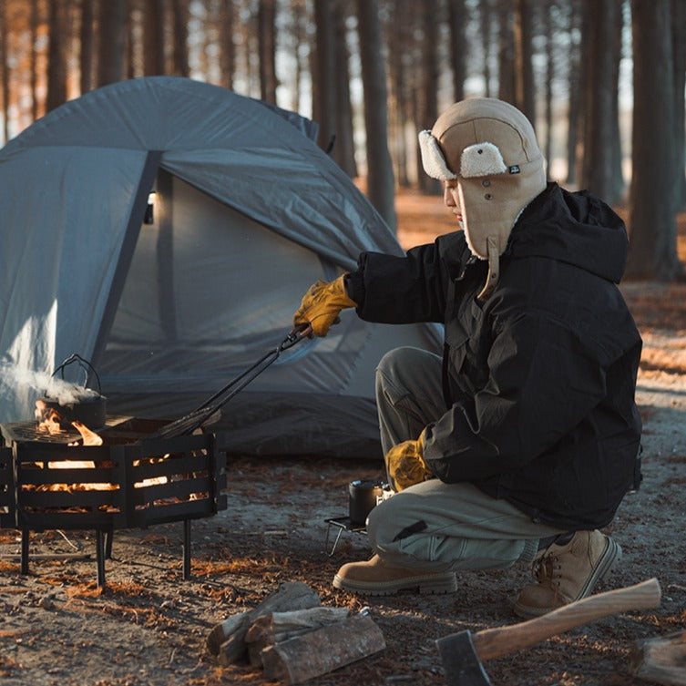 camping fire tongs gripping firewood over outdoor fire pit