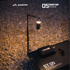 Camping adjustable lantern stand mounted on table providing elevated lighting during nighttime outdoor setup.