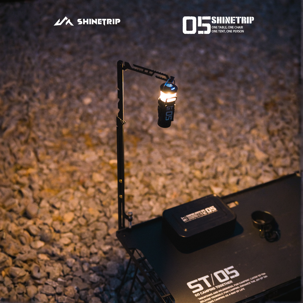 Camping adjustable lantern stand mounted on table providing elevated lighting during nighttime outdoor setup.