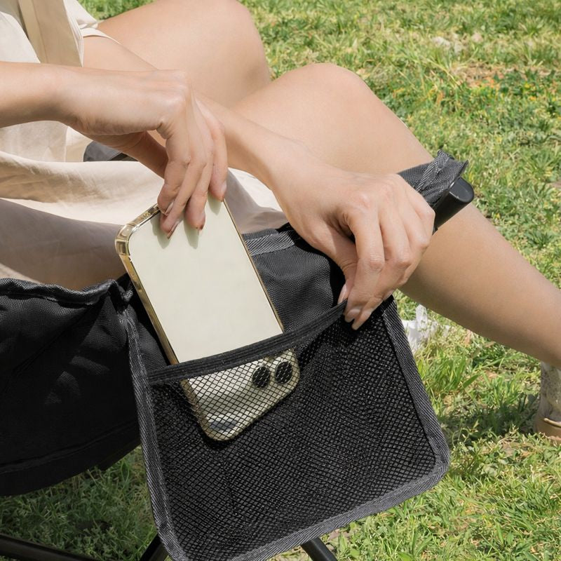 Side storage pocket on padded camping chair for phone, bottle, or personal items